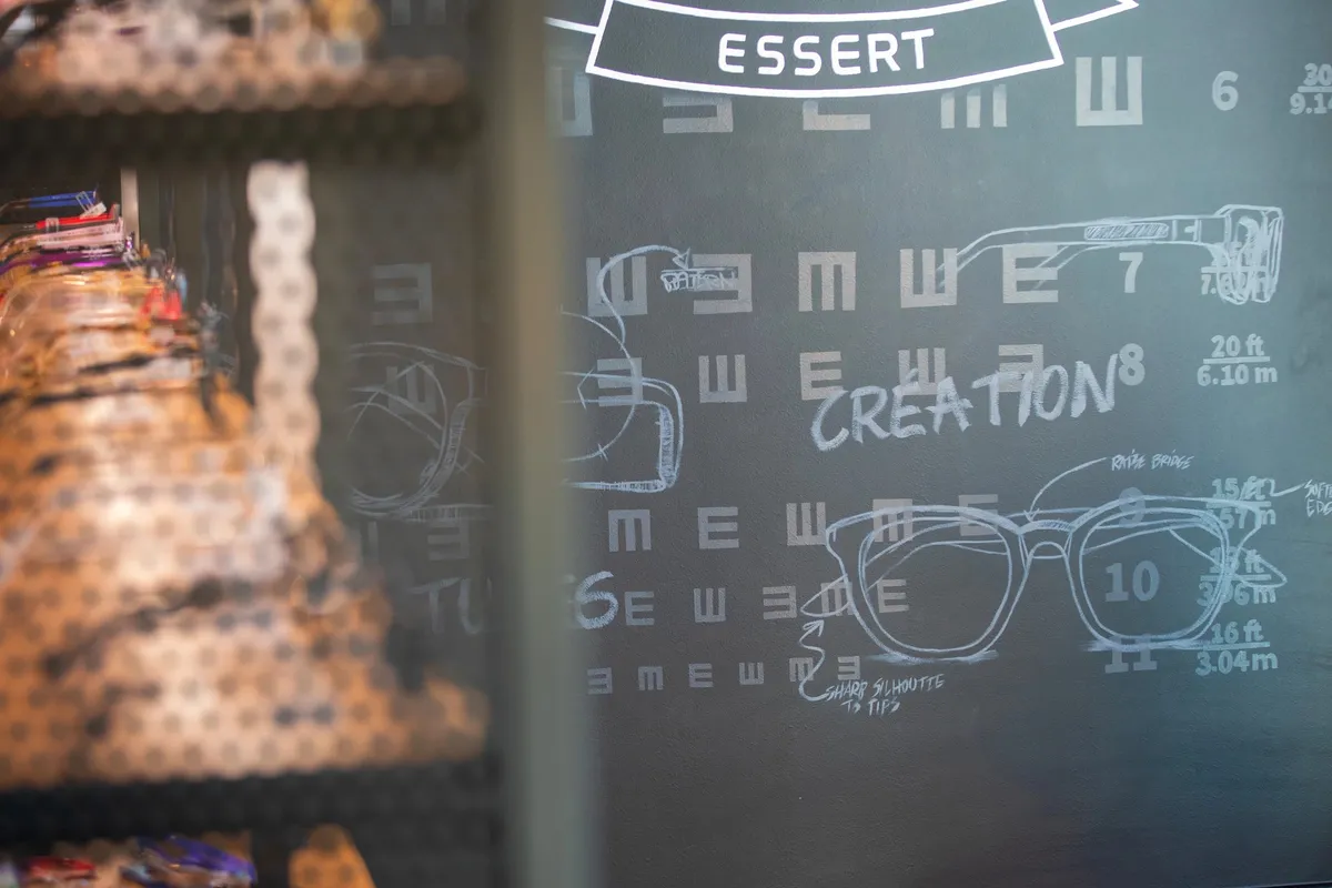 Vitrine de la boutique avec tableau noir dessiné à la craie, silhouettes de montures façon tableau d'acuité visuelle, enseigne « Essert »