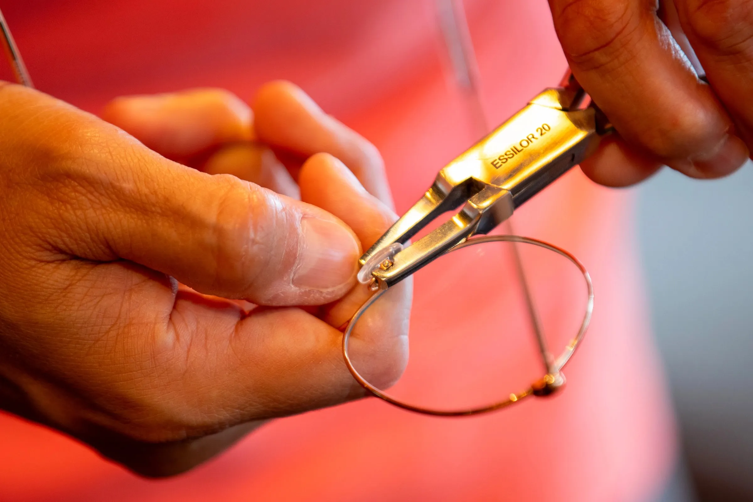 Mains du lunetier ajustant la charnière d'une monture au tournevis, en atelier, à La Boutique des Lunetiers