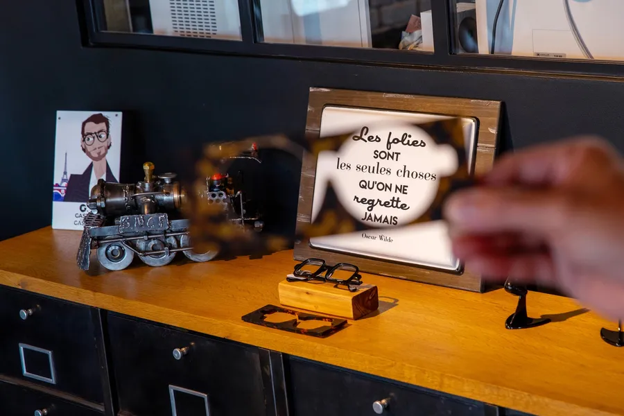 Détail d'ambiance dans la boutique : cadre-citation et objets de décoration sur un meuble, à La Boutique des Lunetiers