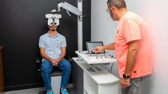 Un professionnel utilise le pupitre d’un réfracteur automatisé pendant l’examen de vue d’une personne assise.