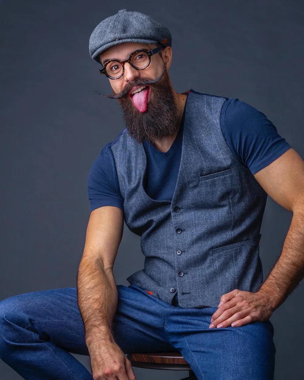 Portrait d'un mannequin barbu, casquette et lunettes rondes en écaille de La Brique et la Violette, expression joueuse