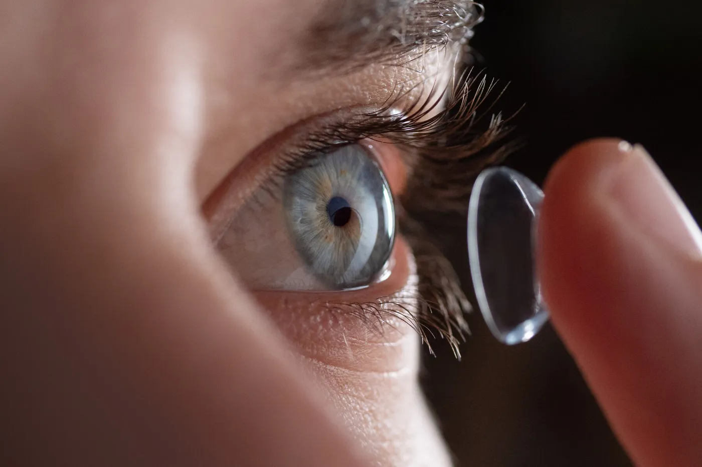 Gros plan sur un œil et une main posant délicatement une lentille de contact