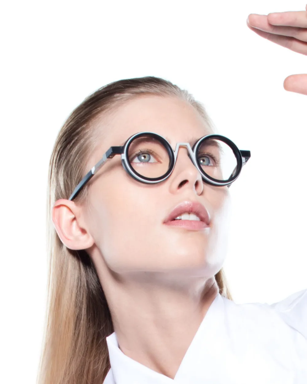 Portrait éditorial d'une femme portant une monture optique ronde VAVA Eyewear, noir et blanc, geste dynamique sur fond blanc
